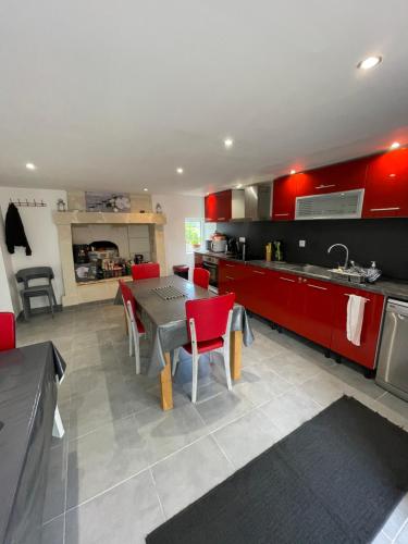 une cuisine avec des armoires rouges et une table et des chaises dans l'établissement Gîte dans le vignoble de Bourgueil, à Le Port Boulet