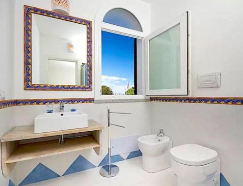 a bathroom with a toilet and a sink and a window at Magnificent Villa: SUPER PANORAMIC in Costa Rei
