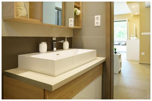 La salle de bains est pourvue d'un lavabo blanc et d'un miroir. dans l'établissement Kenese Regatta Apartman, à Balatonkenese