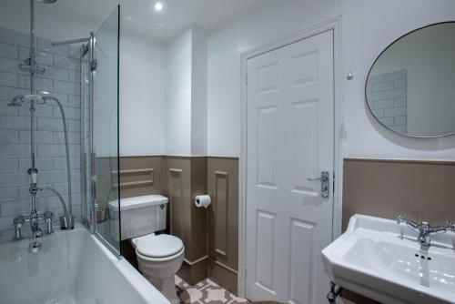 a bathroom with a tub and a toilet and a sink at The Burlington in Worthing