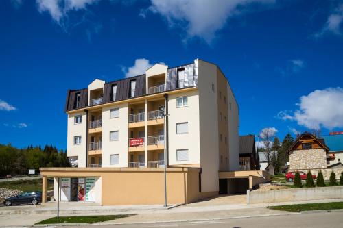 un edificio alto de color blanco con balcones encima en Apartman Orion, en Žabljak