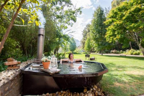 a woman in a hot tub in a yard at Hoogwater Farmhouse in Wolseley