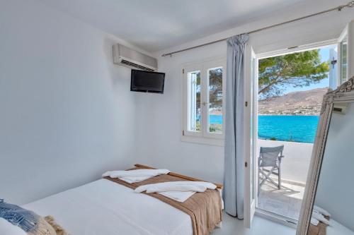 a bedroom with a bed and a view of the ocean at Boutique ''Di Mare'' Hotel & Suites in Posidhonía