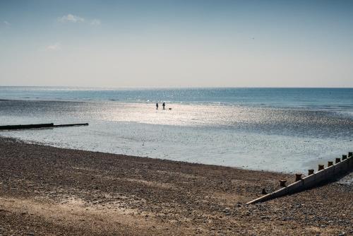 a beach with people walking in the water at The Burlington in Worthing