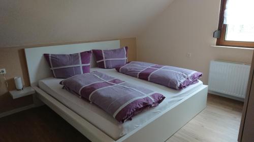 a bedroom with a bed with purple pillows at Weingut Bollig-Prüm in Trittenheim