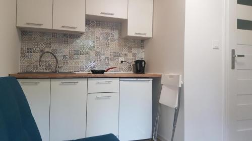 a kitchen with white cabinets and a counter top at Domki u Remika in Pobierowo