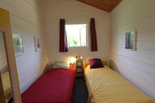 deux lits dans une petite pièce avec une fenêtre dans l'établissement Charmant Chalet LE DAMELI, Village du Soleil, Chalet 61, à Mauroux