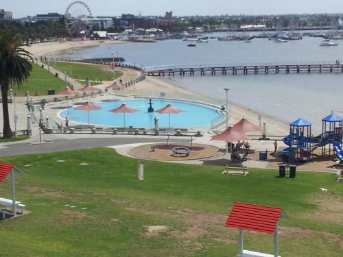 a large swimming pool next to a beach with a pier at Ocean Grove Holiday Park in Ocean Grove