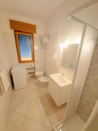 a white bathroom with a toilet and a sink at Terra e Mare in Sorrento