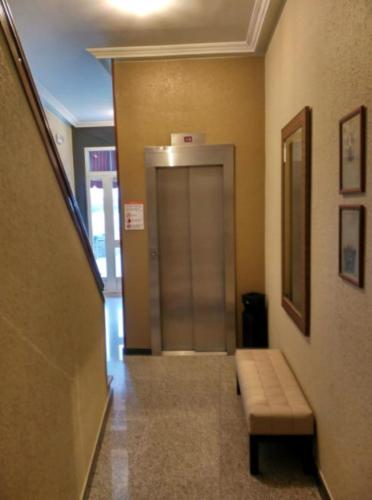 a hallway with a elevator and a bench in a building at Hotel Xeito in Combarro
