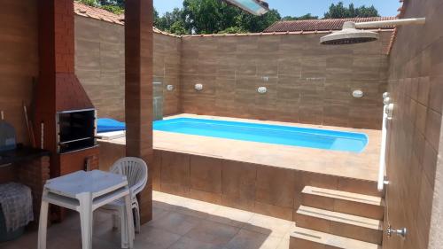 una piscina en un patio trasero con una mesa y una silla en Casa 1, wi fi, ar condicionado, em Mongaguá, en Mongaguá