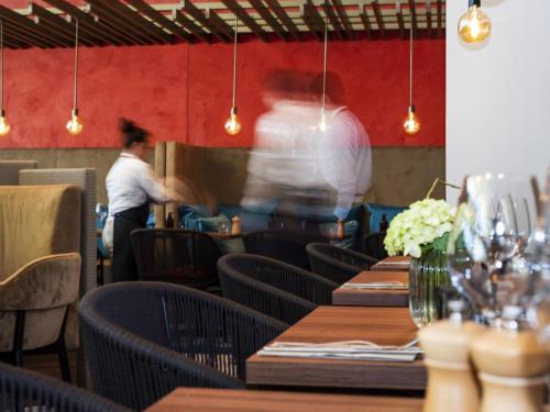 a man working in a restaurant with tables and chairs at Crowne Plaza - Nice - Grand Arenas by IHG in Nice