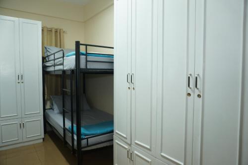 a room with two bunk beds and white cabinets at Mint Homes in CEV Mansion in Manila