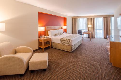 um grande quarto de hotel com uma cama e uma cadeira em Crowne Plaza Monterrey Aeropuerto, an IHG Hotel em Monterrey