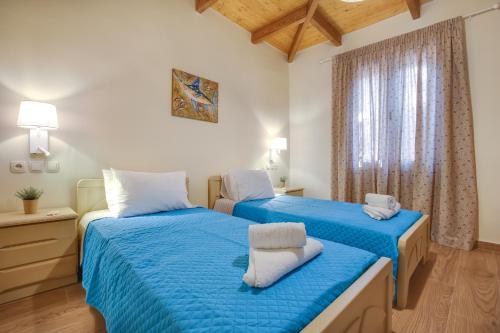 una camera con due letti con lenzuola blu e una finestra di Villa IRENE a Zóla
