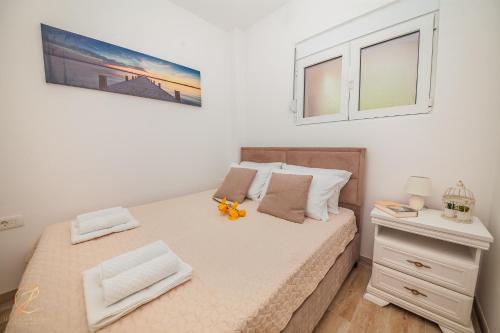 a bedroom with a large bed with two windows at Apartments Ruzmarin in Herceg-Novi