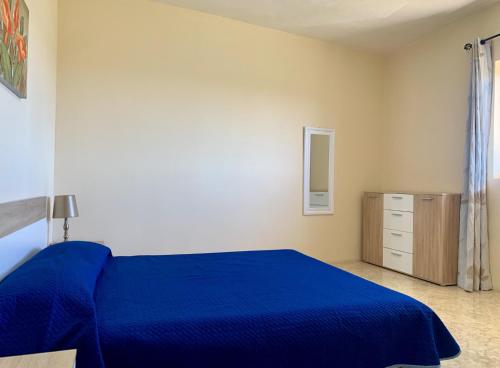 a bedroom with a blue bed and a dresser at Village Apartments in Santa Luċija