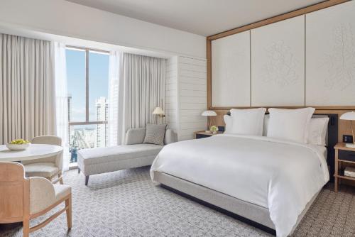 um quarto com uma grande cama branca e uma cadeira em Four Seasons New Orleans em Nova Orleães