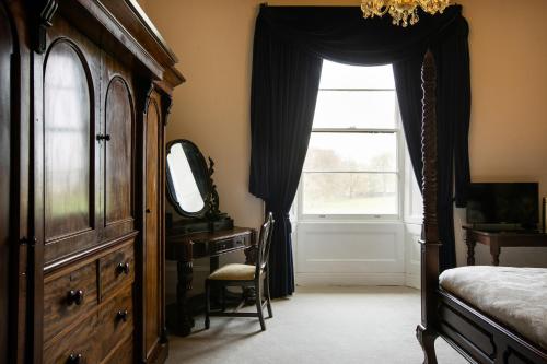 a bedroom with a dresser and a bed and a window at Elm Grove Country House in Tenby