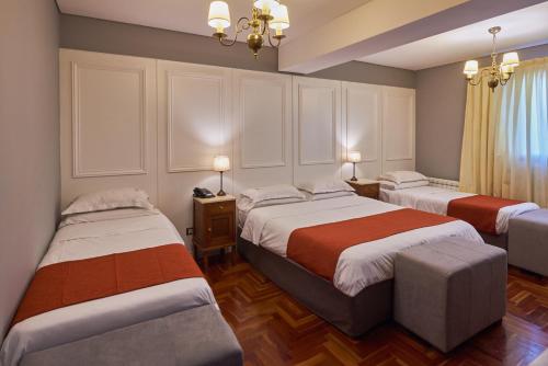 1 dormitorio con 2 camas y lámpara de araña en Altos de Guemes Hotel en Mar del Plata