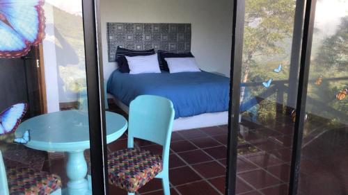 a bedroom with a bed and a table and a chair at Waterfall El Paraíso - Cabañas, jacuzzi, piscina y cascada en medio de la naturaleza in Nocaima