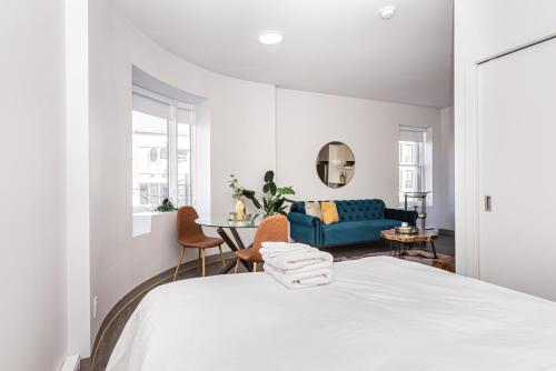 a white bedroom with a bed and a blue couch at Huge New Flat well Located closed on St-Denis Street by Den Stays in Montréal
