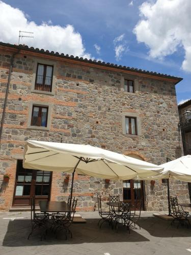 deux tables et chaises avec parasols devant un bâtiment dans l'établissement LA CASA DEL CALZOLAIO, à Radicofani