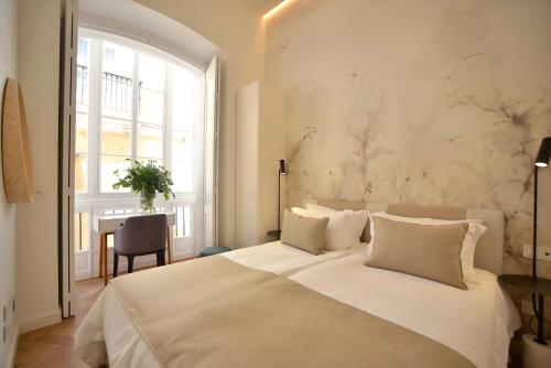 a bedroom with a bed and a table and a window at Plaza Mina Suites - Adults Recommended by Luxury Suites Cadiz in Cádiz