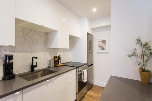 a white kitchen with a sink and a counter top at The Santamaria Golden Palms Studio by Den Stays in Montréal