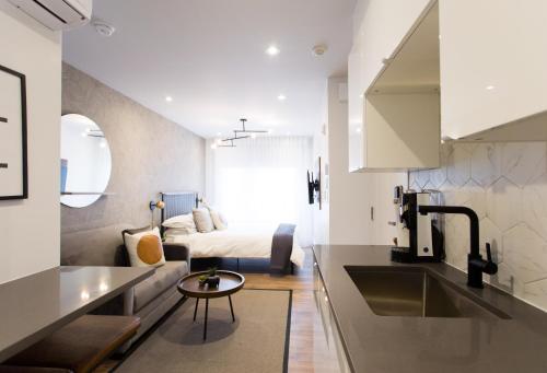 eine Küche und ein Wohnzimmer mit einem Bett im Hintergrund in der Unterkunft Scandinavian Studio with Full Kitchen and Bath by Den Stays in Montreal