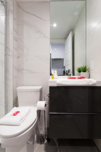 a bathroom with a white toilet and a mirror at Scandinavian Studio with Full Kitchen and Bath by Den Stays in Montréal