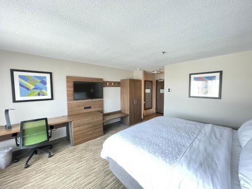 a hotel room with a bed and a desk and a television at Holiday Inn Express South Burlington by IHG in Burlington