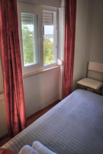 a bedroom with a bed and two windows and a chair at Apartamentos Belo Horizonte in Portimão