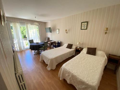 a hotel room with two beds and a dining room at Résidence Les Milandes in Cazaubon