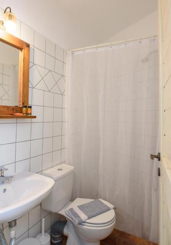 a white bathroom with a toilet and a sink at Uranos Studios in Amorgos