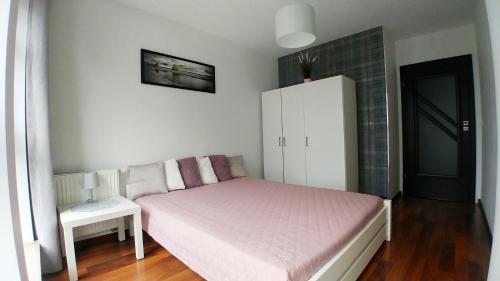 a small bedroom with a bed and a white cabinet at Apartament Bello - free parking in Gdańsk