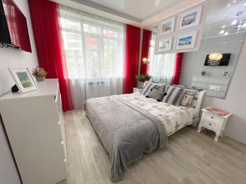 a bedroom with a large bed with red curtains at Apartment Studio PARIS 51 in Irpin'