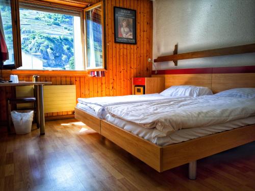 a bedroom with a bed and a desk and a window at Hotel du Stand in Martigny-Ville