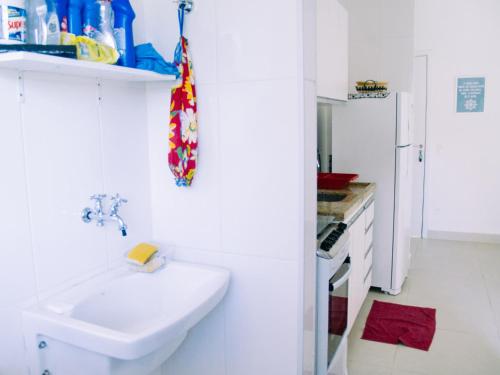 een witte badkamer met een wastafel en een witte koelkast bij Rubi 101 - 100 mts da praia in Ubatuba