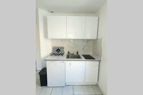 une cuisine avec des armoires blanches et un évier dans l'établissement Grand studio Nice Centre - bord de mer, à Nice