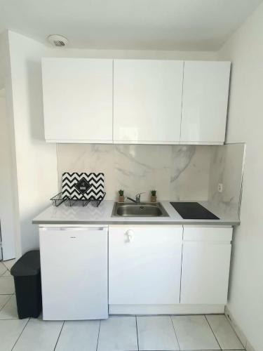 une cuisine avec des armoires blanches et un évier dans l'établissement Grand studio Nice Centre - bord de mer, à Nice