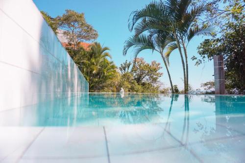 a swimming pool with a palm tree in the background at Banana Leaf Eco Hostel in Barra de Guaratiba