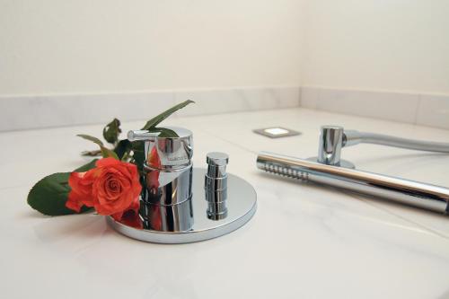 a flower in a silver container on a counter next to a sink at Alpinhotel Berchtesgaden in Berchtesgaden