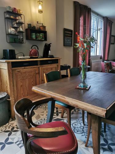 une table de salle à manger avec un vase de fleurs dessus dans l'établissement L'en vert appartement, à Bagnères-de-Bigorre