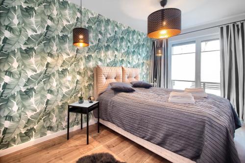 a bedroom with a bed and a wall with leaves at Apartament AP4 in Mielno