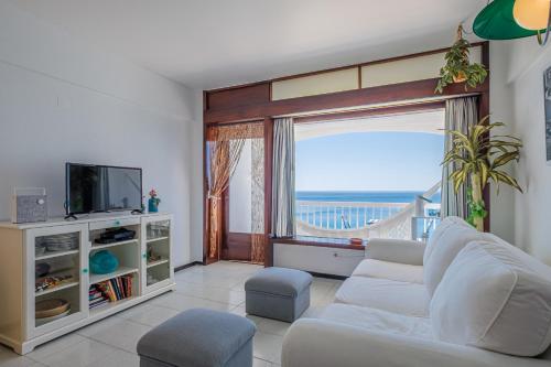 a living room with a white couch and a large window at House on the Beach in Sesimbra