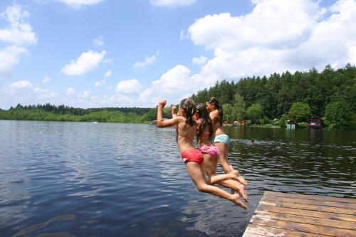 two girls jumping off a dock into a lake at Kirchenwirt Mayr in Franking