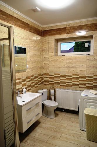 a bathroom with a toilet and a sink and a tub at Henrietta - Violetta Apartman in Hajdúszoboszló
