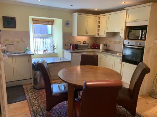 a kitchen with a wooden table and a table and chairs at Abbey Cottage, Findhorn in Findhorn