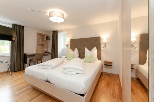 a bedroom with a large white bed with white pillows at Hotel & Restaurant Fischer in Altenstadt